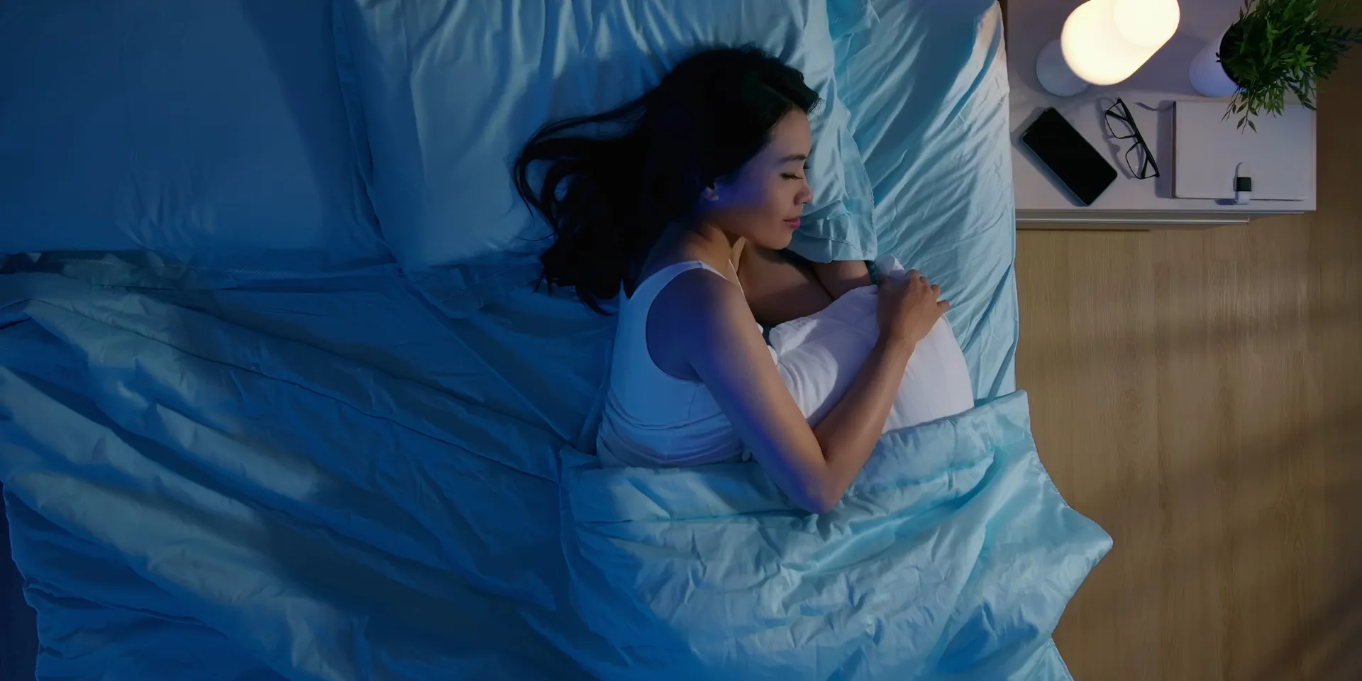 Slapende vrouw in een bed met een tafellamp op het nachtkastje